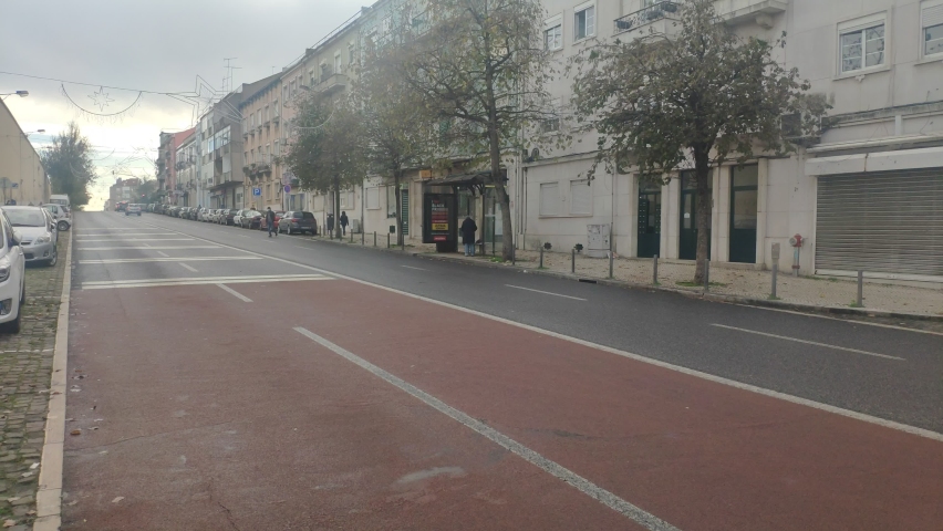Calm street in a cloudy day. No cars passing, and almost no people walking. Old buildings.