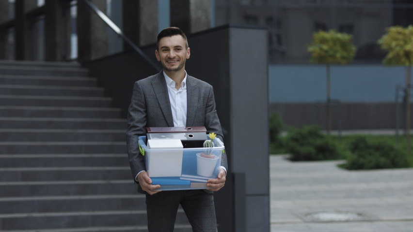 Male office worker with box of personal stuff resigns from his job. Business style suit. Coronavirus outdoors social distancing. Finance and industry. Royalty-Free Stock Footage #1063110733