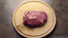 Timelapse video of cooking beef steak at home.Flat lay footage filmed directly from above on kitchen table.Fresh raw piece of tenderloin beefsteak being prepared for grilling for dinner