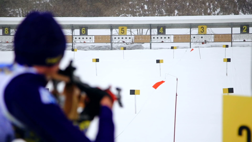 A skier shoots a rifle at a target. Skier takes part in the biathlon race, standing aimed at the target and made a shot.