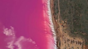 aerial filming. circle drone movement above beautiful bright colorful landscape with pink salt lake coast. orange tent and car on clay lake shore in wild nature top view from above. clip has noise