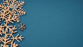 Blue Christmas background video with empty space for text.Beautiful handmade snowflakes made from natural wood material.Footage moving down with space for invitational text,filmed in 4K ultra hd