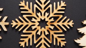Flat lay video clip of wooden snowflakes for home decor filmed directly from above in 4K ultra hd.Handmade snow flake and Christmas tree toys footage shot on black background with zoom out effect