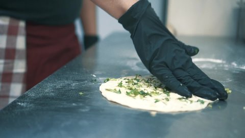 hands preparing flat bread naan garlic bread with coriander close up chef wearing gloves in hygienic environment kitchen