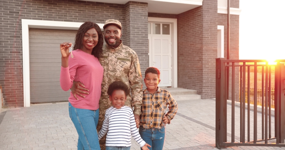 Portrait of African American family of army officer with little kids moving in new house and showing keys. Outdoor in yard at home. Mother, father soldier, son and daughter demonstrating key. Royalty-Free Stock Footage #1063115995