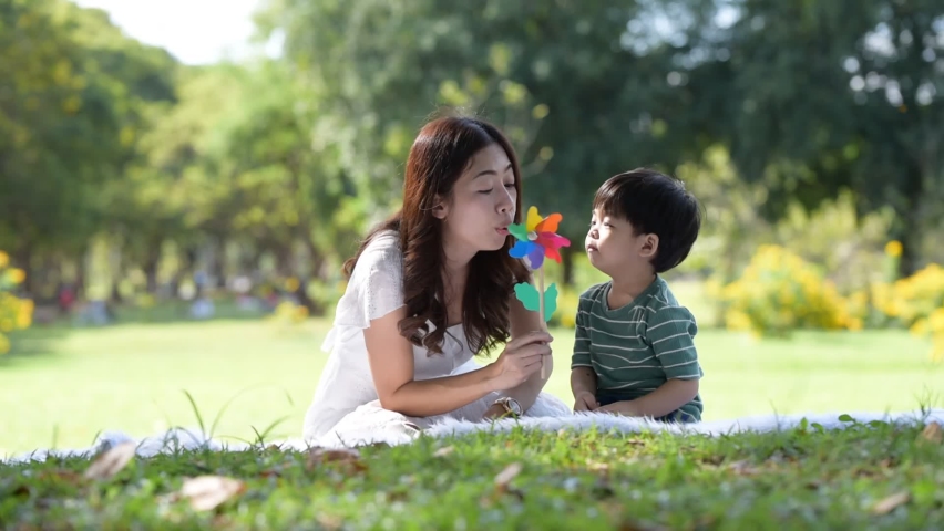 Happy Asian family having fun mother and her son playing windmill in the garden together