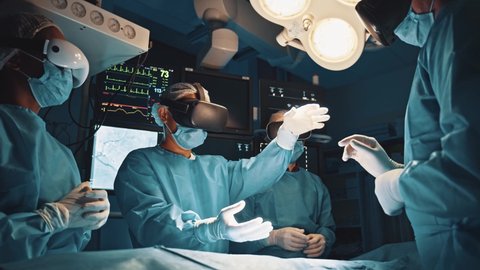 Mixed race surgeons performing heart surgery using futuristic technology VR headsets virtual transplant operation interactive simulation in operating room. Visualization. Medical.