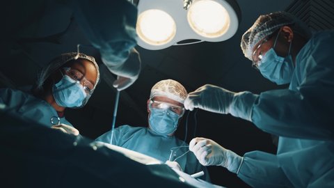 Professional surgeon performing operation with diverse nurses and interns. Group of medical workers doing surgery in operating room. Hospitals.