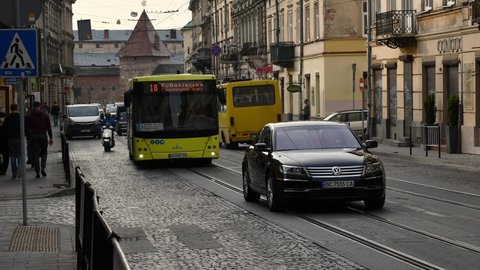 European town street time lapse. Busy car traffic and people walking by crosswalk over cobblestone road of ancient architecture cityscape. Community yellow bus transportation. Lviv, Ukraine 10 09 2020