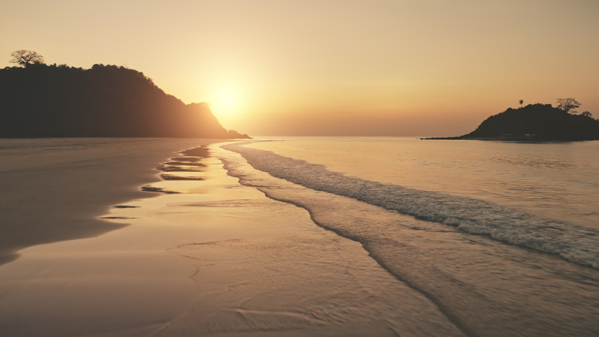 Sunset over ocean waves wash sand beach. Aerial sun set above mountain silhouette. Tropic nobody nature seascape. Paradise island of El Nido, Philippines, Asia at sea bay. Cinematic drone shot | Shutterstock HD Video #1063126510