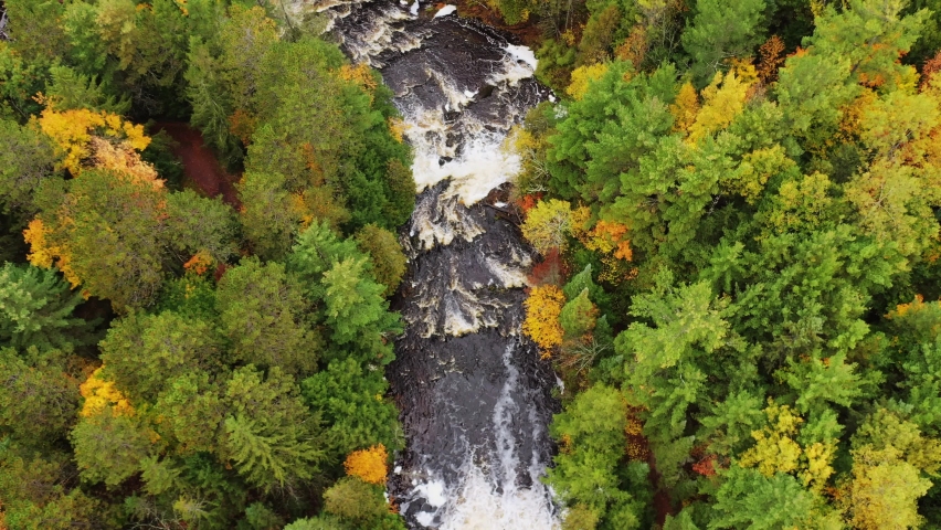 Beautiful aerial flying over the cascades and Brownstone Falls on Tyler Forks river as it merges with Bad River with colorful fall foliage lining the river banks in autumn at Copper Falls park.