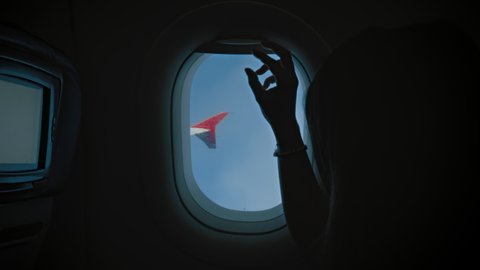 Clean minimalistic shot, fade to black when female passenger close window blind in airplane. View on plane wing and woman close window to sleep or rest during long transatlantic flight