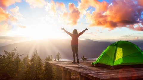 Cinemagraph Continuous Loop Animation. Adventure Girl and Camping Tent on top of Mountain and Canadian Nature Landscape during colorful sunset. Bowen Island, near Vancouver, British Columbia, Canada.