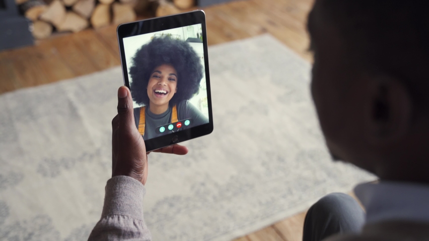 African american man video calling girlfriend on digital tablet. Black couple talking dating by virtual meeting via conference videocall. Remote relationship, online chat concept, over shoulder view. | Shutterstock HD Video #1063130524