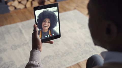African american man video calling girlfriend on digital tablet. Black couple talking dating by virtual meeting via conference videocall. Remote relationship, online chat concept, over shoulder view.