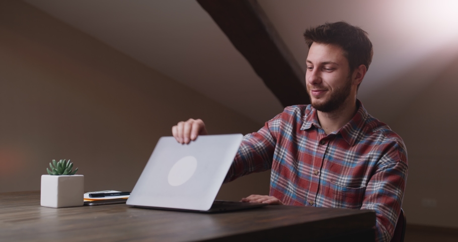 End of video conference. Young man waving hand good bye to laptop screen, saying goodbye to chat colleagues and closing laptop, sitting at workplace at home office Royalty-Free Stock Footage #1063132789