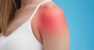 Muscle pain concept. Close up shot of sore female shoulder with red inflamed pulcating spot, blue background