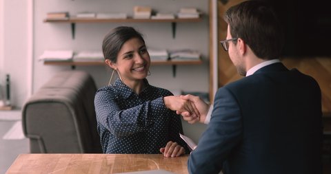 Indian ethnicity 25s confident female applicant passing job interview finish formal appointment shaking hands with male employer. Successful business meeting, making deal, hr, company staffing concept