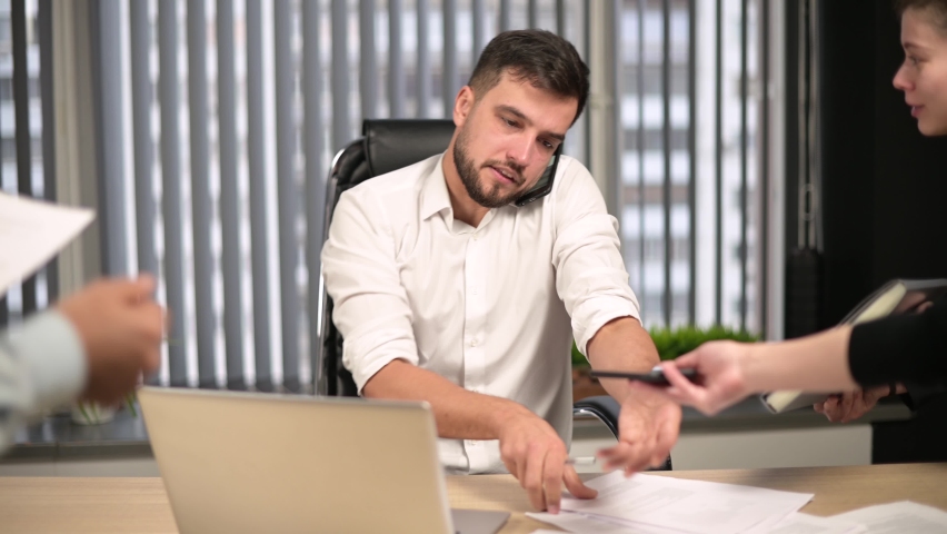 Colleagues and executives overwhelmed the young male head of the office with work. Too much work for one person, overload | Shutterstock HD Video #1063139779