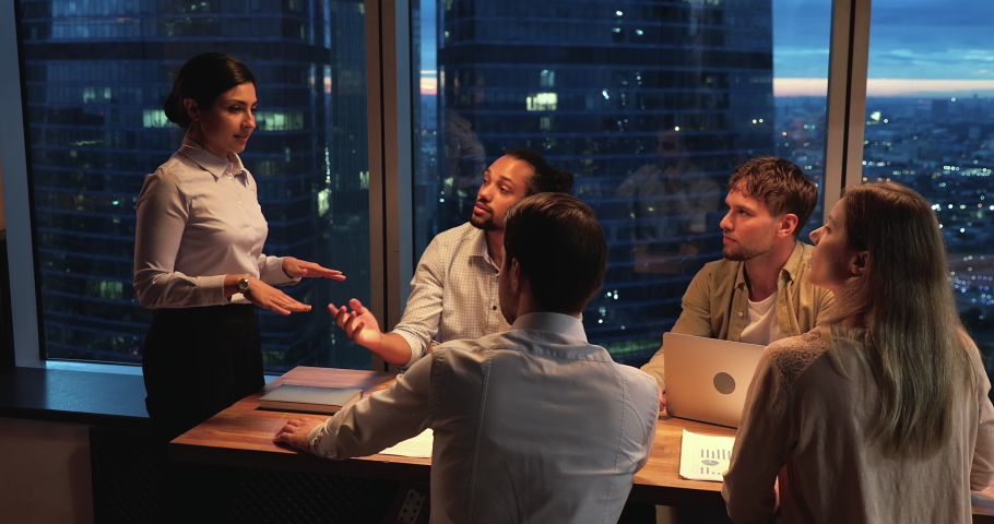 Team of young motivated ambitious startupper working until late in modern office boardroom, skyscrapers night city view through panoramic window. Accomplish successful meeting giving high five gesture Royalty-Free Stock Footage #1063141597