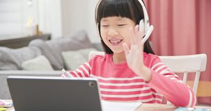asian girl is wearing headset and learning online through digital tablet at home