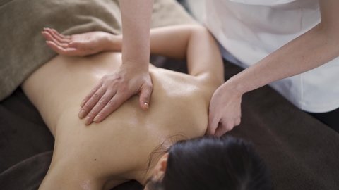 Japanese woman receiving a back massage at an aesthetic salon