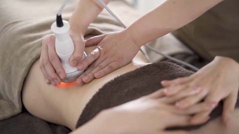 Japanese woman to warm up cellulite in the tummy at an aesthetic salon