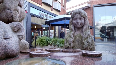 Warrington , United Kingdom (UK) - 02 27 2020: Mad hatter tea party granite carved sculpture in Warrington town Golden square slow pull back reveal