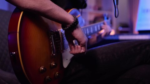 Close-up of a man's hands playing on a electric guitar. Musician plays an electric guitar, closeup shot.  Human hands plays on a guitar neck, soft focus