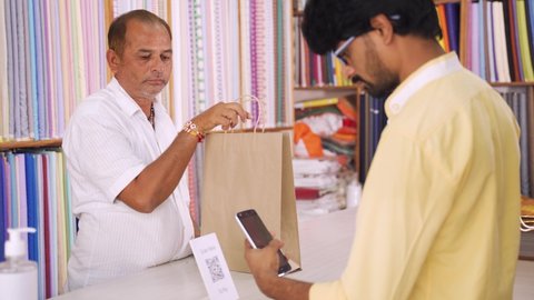 Customer using digital payment method scan to pay at cloth store to send money - concept of digital or contactless payment, e-transfer, technology and lifestyle