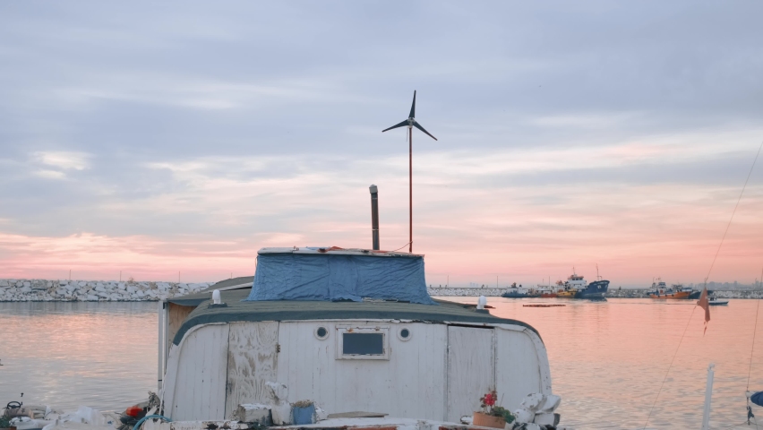 Weather vane on top of the moored ship in the harbor under pink blue sky at sunset
