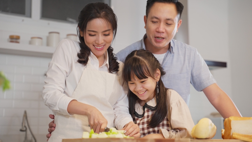 Family relationship, Asian happy family making food preparation in kitchen room at house. Father mother and children having fun spending time together. Dad and little girl looking at mom cooking food. Royalty-Free Stock Footage #1063161967