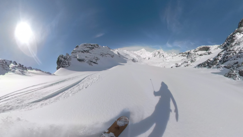POV: Shredding virgin powder snow while riding off trail in the scenic white Canadian Rockies. Cool first person shot of snowboard touring in the Rocky Mountains on a picturesque sunny winter day. Royalty-Free Stock Footage #1063162336