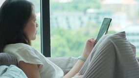 4K Video 30 years old asian woman sit on sofa and using mobile phone. Theme for technology and lifestyle at home.