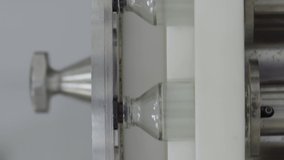 Vertical video glass bottles filled and sealed with rubber caps on a medical solution conveyor line close up medical industry