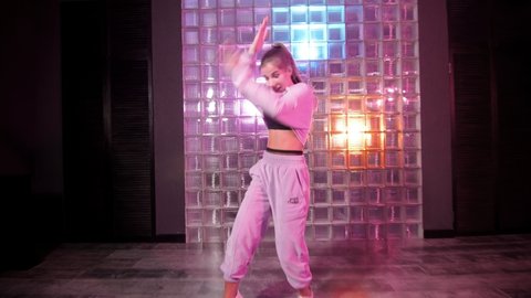 Stylish young woman dancing hip hop, freestyle in the studio. Gimbal shot. Youth lifestyle and emotions concept.