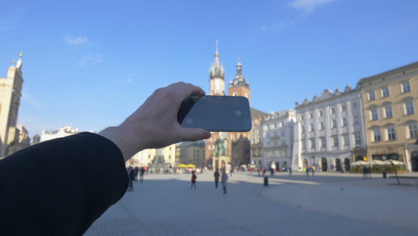 Man taking picture of old town in Krakow in Poland in 4k slow motion 60fps