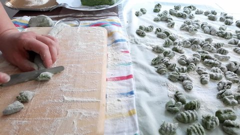 Real time video of female hands making raw spinach and potato gnocchi. Fresch green homemade italian dough dumplings on a towel.