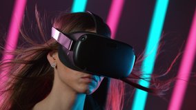 Slow motion of young woman with VR glasses, virtual reality with neon lights. Filmed on high speed cinema camera.