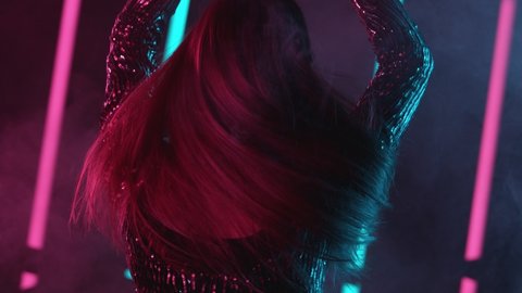 Slow motion of young woman dancing with neon lights background, backside. Filmed on high speed cinema camera.