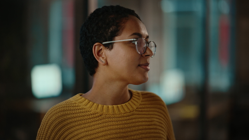 Close Up Portrait of a Young Latina with Short Dark Hair and Glasses Posing for Camera in Creative Office. Beautiful Diverse Multiethnic Hispanic Female Wearing Yellow Jumper is Happy and Smiling. Royalty-Free Stock Footage #1063172863