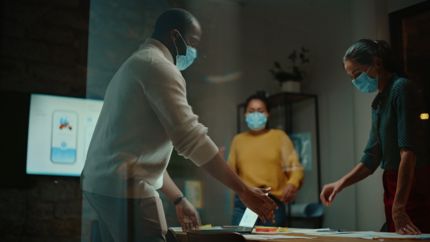 Diverse Multiethnic Team Wearing Face Masks During a Meeting Room Conversation Behind Glass Walls in Creative Office. Social Distancing Restrictions Concept in Work Place During Coronavirus Pandemic. Royalty-Free Stock Footage #1063172887