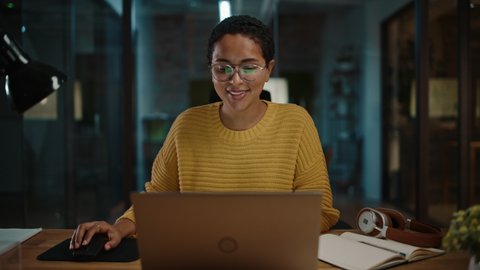 Zoom In Portrait of Young Latina Marketing Specialist Working on Laptop Computer in Busy Creative Office Environment. Beautiful Diverse Multiethnic Female Project Manager is Browsing Internet.