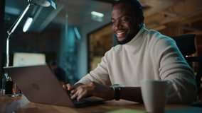 Handsome Black African American Man Having an Online Conversation on a Laptop Computer in Creative Office Environment. Happy Male is Browsing Social Media and Replying to Friends in Messenger. - Powered by Shutterstock - Get 15% off with code: PIKWIZARD15