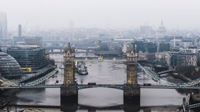 Establishing Aerial View Shot of London UK, Red Bus crossing Tower Bridge, city disappear in mist, United Kingdom, fog covering capital