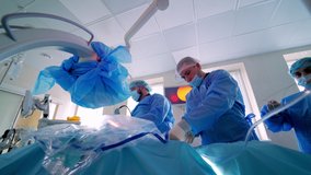 Group of doctors in the operating room. Medical specialists in blue masks and uniform are performing an operation in clinic. Medical surgery. Video.