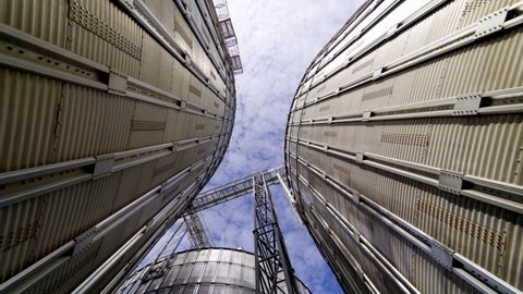 Metal tanks of elevator. Grain-drying complex outdoors. Commercial grain silos on sky background. Steel storage for agricultural harvest. Close-up.