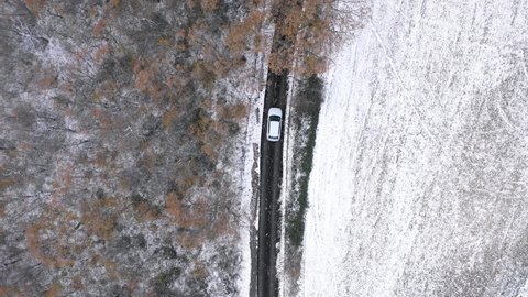 Aerial top view of car driving on snow countryside road - Aerial video of winter scene in Italy with white countryside - Travel and nature concepts