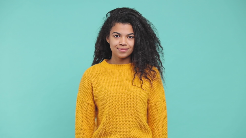 Surprised overjoyed young african american woman in yellow sweater isolated on blue background studio. People lifestyle concept. Doing winner gesture clenching fists applause cheering clapping hands Royalty-Free Stock Footage #1063185433