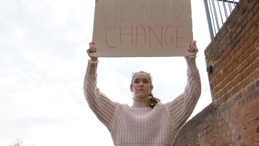Strong woman standing in protest holding a sign for change on a street low angle Royalty-Free Stock Footage #1063186183